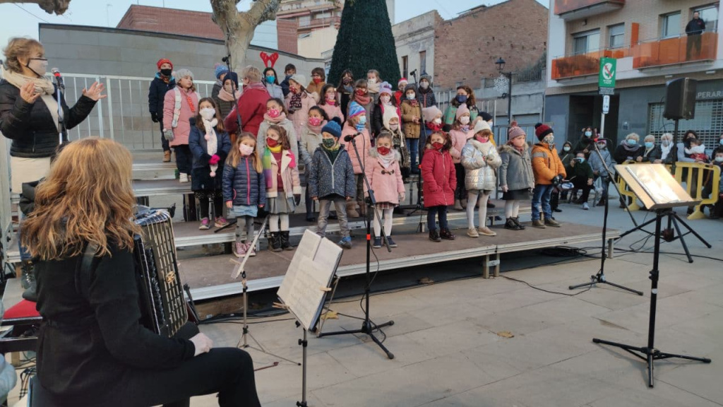 Escenari a la plaça de l'ajuntament amb tots els nens i nenes amb mascaretes, alumnes de l'Escola de Música, fent l'actuació