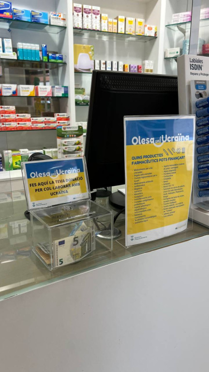 mostrador d'una farmacia amb una guardiola per recollir diners i un cartell informatiu