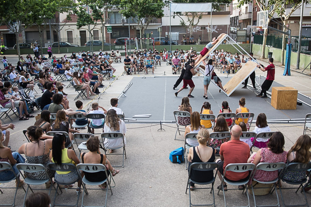 Assistents asseguts veient al grup de dansa en el pati de l'Escola Montserrat fent acrobàcies